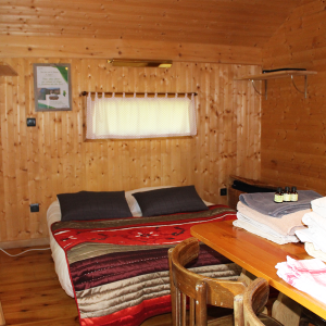 Chalet en bois chaleureux avec lit douillet et décoration rustique à Bourgogne-Franche-Comté.
