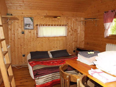 Chalet en bois chaleureux avec lit douillet et décoration rustique à Bourgogne-Franche-Comté.
