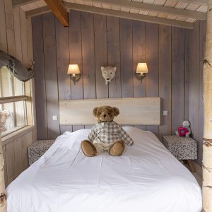 Cabane en bois avec lit douillet et ours en peluche sur la couette.