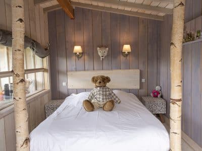Cabane en bois avec lit douillet et ours en peluche sur la couette.