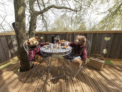 Hébergement insolite en Hauts-de-France : oursons en peluche autour dune table en bois.