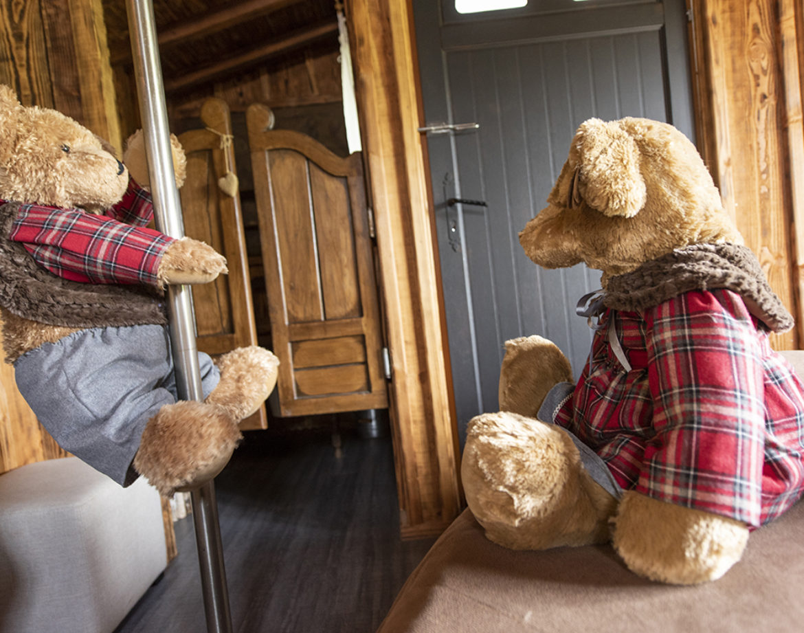 Hébergement insolite en bois avec des peluches sur un poteau et un lit confortable.