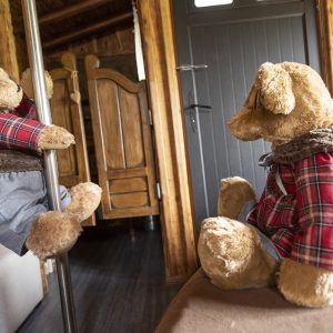 Hébergement insolite en bois avec des peluches sur un poteau et un lit confortable.