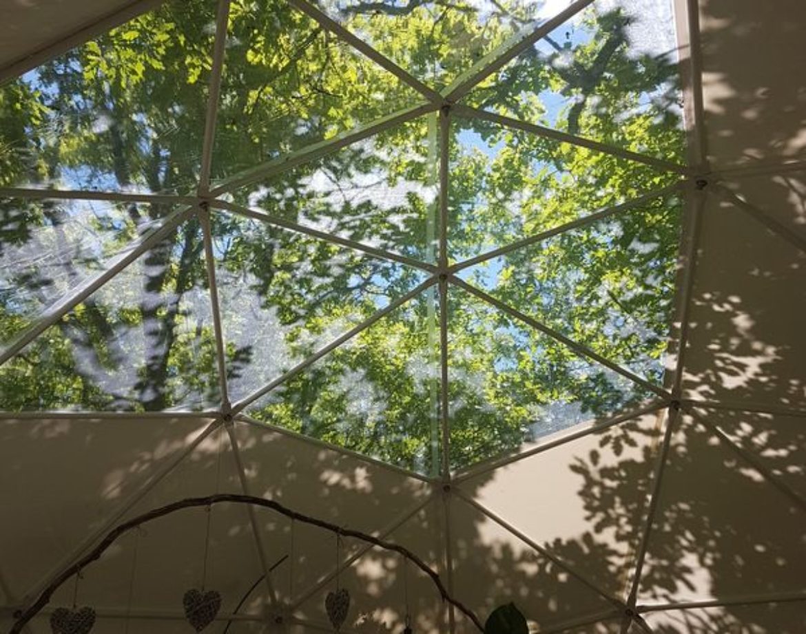 Hébergement insolite en dôme avec vue sur le ciel et la verdure environnante.