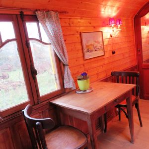 Intérieur chaleureux dune roulotte, avec table en bois et fenêtres lumineuses.