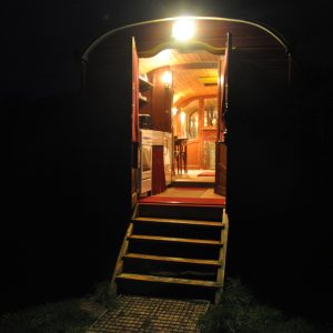 Roulotte cosy illuminée, avec une entrée en bois et une ambiance chaleureuse.