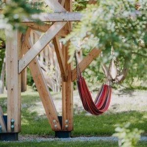 Hébergement insolite en cabane avec hamac suspendu, entouré de verdure.