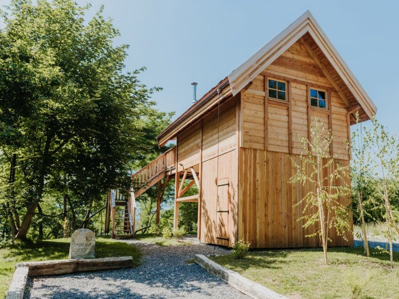 Charmante cabane en bois sur pilotis, entourée de verdure et de lumière naturelle.