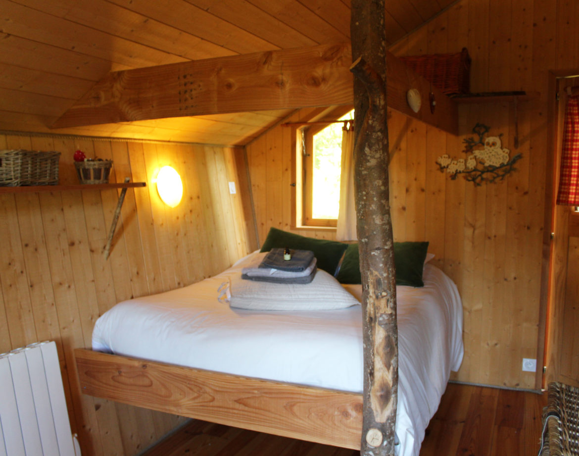 Cabane en bois cosy avec lit suspendu et décoration naturelle en Bourgogne-Franche-Comté.