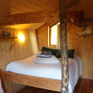 Cabane en bois cosy avec lit suspendu et décoration naturelle en Bourgogne-Franche-Comté.