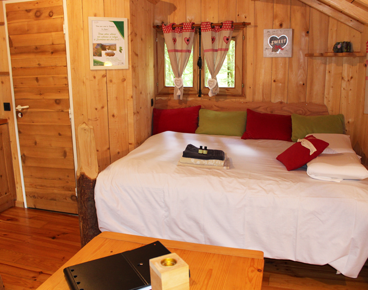 Chalet en bois chaleureux avec lit douillet et décor coloré à Bourgogne-Franche-Comté.