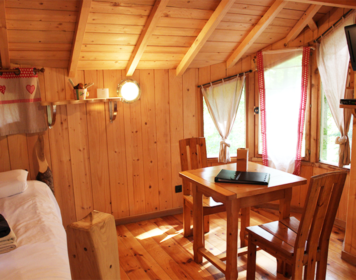 Cabane en bois cosy avec table en bois et lumière naturelle à Bourgogne-Franche-Comté.
