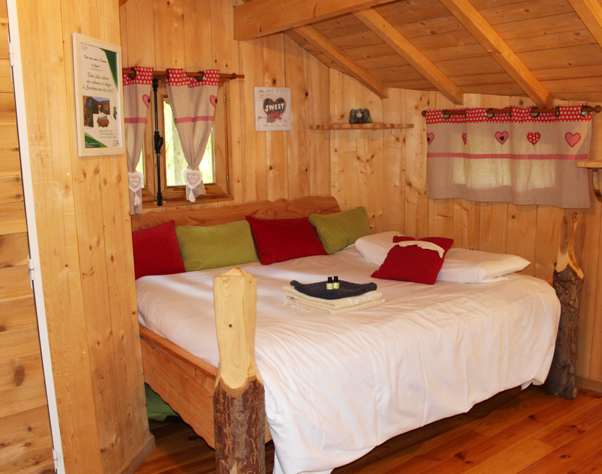 Chalet en bois chaleureux avec lit douillet et décor coloré à Bourgogne-Franche-Comté.