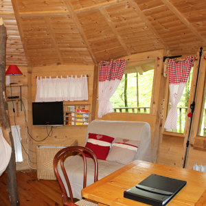 Cabane en bois cosy avec fenêtres à carreaux et décoration chaleureuse.