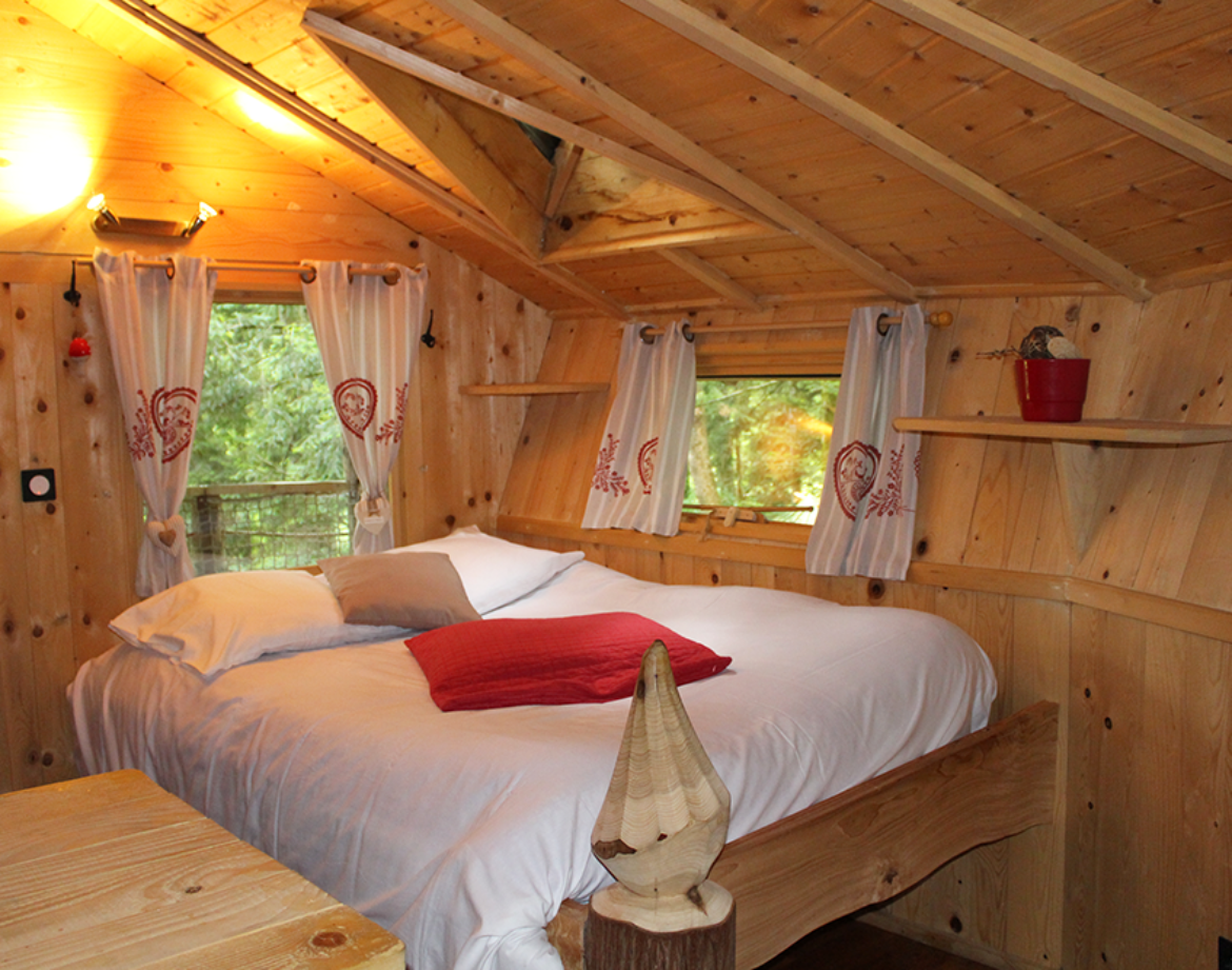 Chalet en bois chaleureux avec lit douillet et décor naturel en Bourgogne-Franche-Comté.