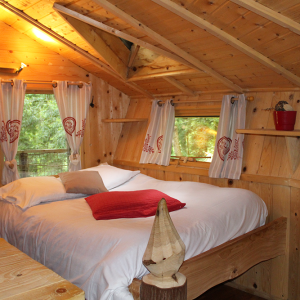 Chalet en bois chaleureux avec lit douillet et décor naturel en Bourgogne-Franche-Comté.