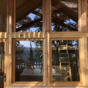 Cabane en bois avec grandes fenêtres, offrant une vue sur la nature environnante.