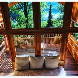 Cabane en bois avec vue sur la nature, balcon en bois et lumière naturelle.