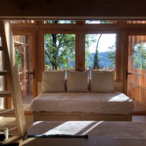 Cabane en bois avec grandes fenêtres offrant une vue sur la nature environnante.