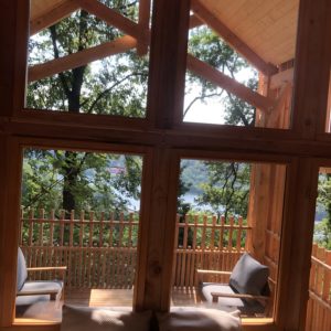 Cabane en bois avec vue sur le lac, entourée de verdure et de lumière naturelle.