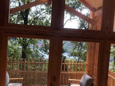 Cabane en bois avec vue sur le lac, entourée de verdure et de lumière naturelle.