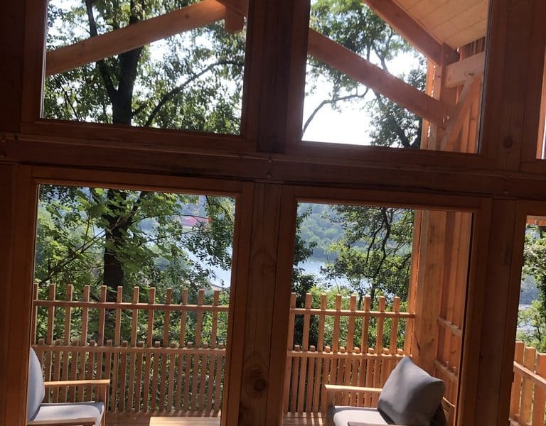 Cabane en bois avec vue sur le lac, entourée de verdure et de lumière naturelle.