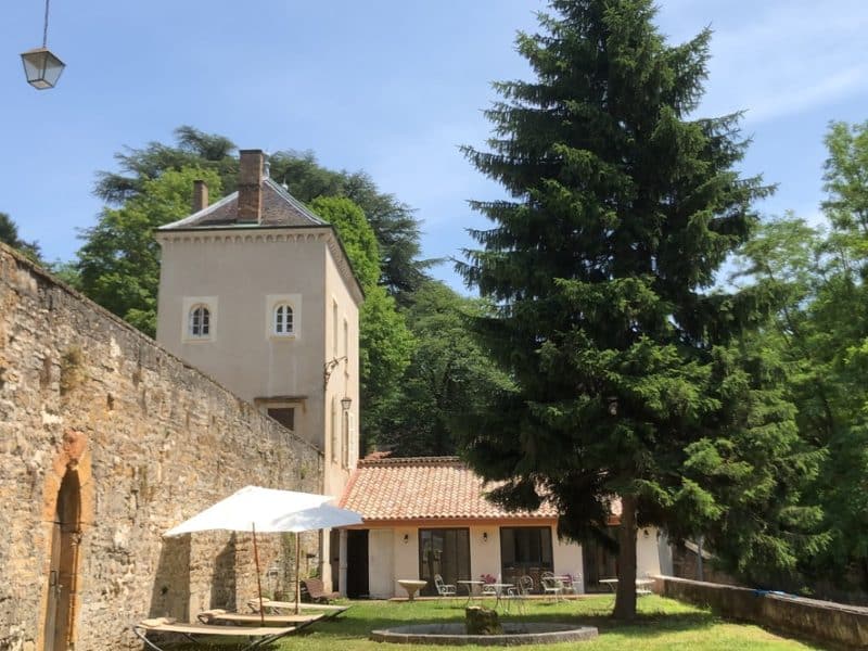 Charmante maison dhôtes avec terrasse, entourée darbres verdoyants.