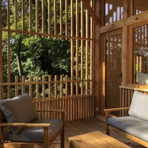 Cabane en bois avec terrasse, offrant une vue imprenable sur la forêt verdoyante.