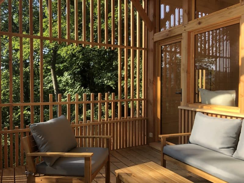Cabane en bois avec terrasse, offrant une vue imprenable sur la forêt verdoyante.