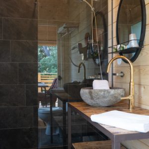 Salle de bain moderne dun hébergement insolite en bois, avec douche en verre et lavabo en pierre.