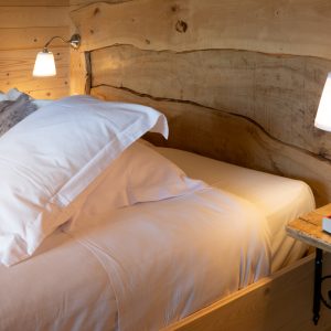 Chalet en bois dans le Languedoc-Roussillon, lit douillet avec tête de lit en bois naturel.
