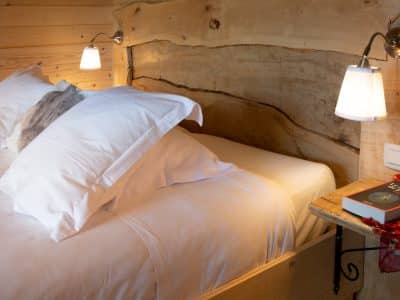Chalet en bois dans le Languedoc-Roussillon, lit douillet avec tête de lit en bois naturel.