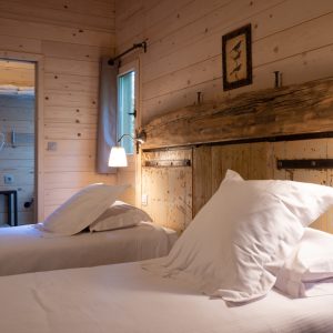 Chalet en bois chaleureux avec lits jumeaux et ambiance naturelle apaisante.