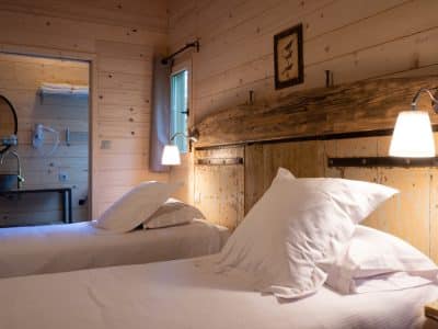 Chalet en bois chaleureux avec lits jumeaux et ambiance naturelle apaisante.