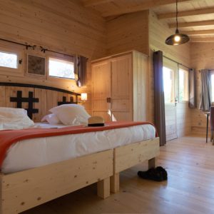 Chalet en bois chaleureux avec lit douillet et vue sur la nature environnante.