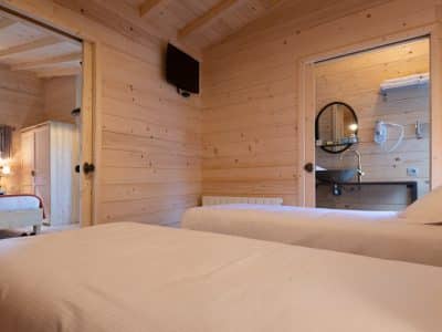 Chalet en bois chaleureux avec lits jumeaux et salle de bain moderne.