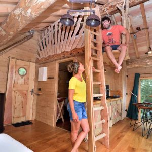 Cabane en bois perchée avec échelle, ambiance chaleureuse et naturelle.