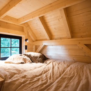 Cabane en bois cosy avec un lit douillet et des murs en bois clair.