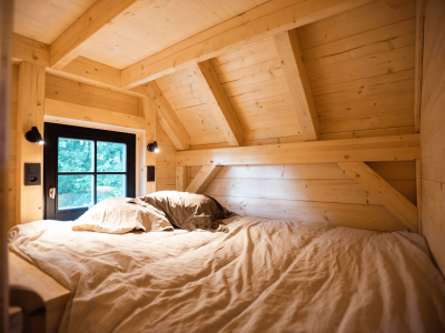 Cabane en bois cosy avec un lit douillet et des murs en bois clair.