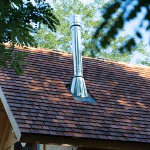 Cabane en bois avec cheminée en métal, nichée au cœur de la nature.