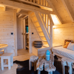 Cabane en bois chaleureuse avec un intérieur lumineux et des meubles en bois naturel.