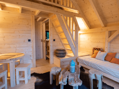 Cabane en bois chaleureuse avec un intérieur lumineux et des meubles en bois naturel.
