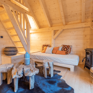 Cabane en bois à Midi-Pyrénées, intérieur chaleureux avec poêle et mobilier en bois.