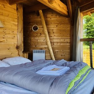 Cabane en bois avec lit douillet et vue sur la nature environnante.