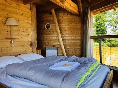 Cabane en bois avec lit douillet et vue sur la nature environnante.