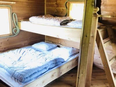 Cabane en bois avec lits superposés et ambiance chaleureuse en Auvergne-Rhône-Alpes.