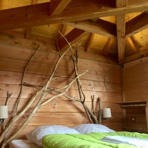 Chalet en bois avec un lit confortable et des branches décoratives au mur.