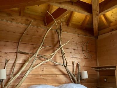 Chalet en bois avec un lit confortable et des branches décoratives au mur.