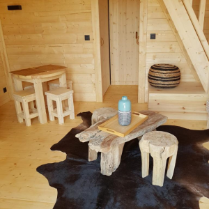 Hébergement insolite en bois à Midi-Pyrénées, avec mobilier en bois et tapis en peau.