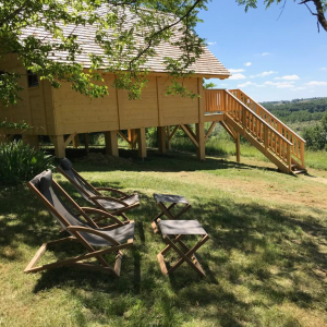 Cabane en bois perchée, entourée dun jardin verdoyant et de chaises longues confortables.
